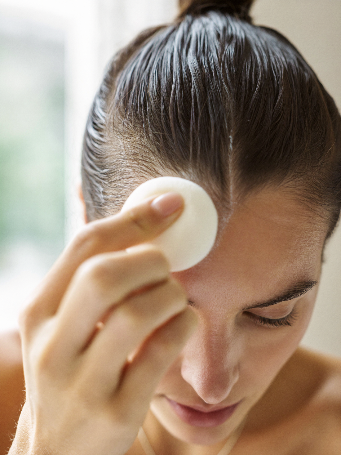Close-up of a puff being pressed along the hairline and part line